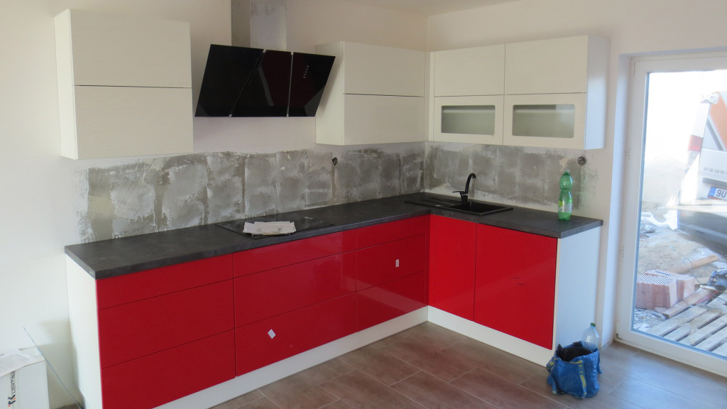 Kuchyň v červeno-bílé kombinaci s tmavou pracovní deskou čeká na obklad